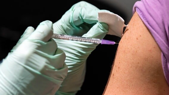 Ein Mann lässt sich bei gegen Covid-19 in den Oberarm impfen. © dpa Foto: Bernd von Jutrczenka