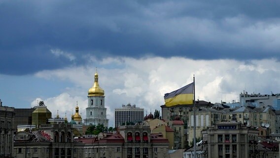 Eine ukrainische Flagge weht vor Gebäuden in Kiew. © AP/dpa Foto: Natacha Pisarenko