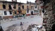 Kinder laufen zwischen Gebäuden, die während der Kämpfe in Mariupol zerstört wurden © Uncredited/AP/dpa 