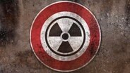 Ein Warnzeichen für nukleare Gefahr (Warnung vor Radioaktivität, Strahlung und Atomwaffe) hängt an einer Wand (Fotomaontage). © picture alliance/CHROMORANGE Foto: Michael Bihlmayer