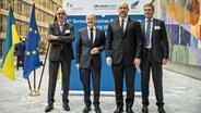 Der Präsident des DIHK, Peter Adrian (links), Bundeskanzler Olaf Scholz (2. von links), neben dem Premierminister der Ukraine, Denis Schmyhal (2. von rechts) und der Vizepräsident des Ostausschusses, Ulrich Engel (rechts), kommen zum deutsch-ukrainischen Wirtschaftsforum "Rebuild Ukraine" in Berlin zusammen. © dpa Foto: Michael Kappeler