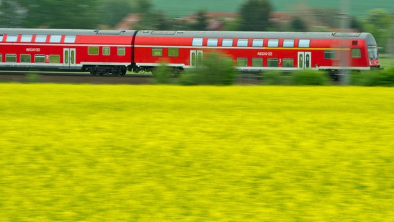 Ein Regionalzug fährt in der Landschaft an Feldern vorbei. © picture alliance Foto: picture alliance/dpa | Patrick Pleul