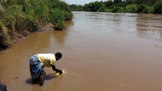 Eine afrikanische Frau füllt aus einem Fluss in Kenia Wasser in einen Kanister.  Foto: privat