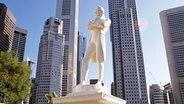 Die Statue des Gründers der Metropole Singapur Sir Stamford Raffles, im Hintergrund eine Hochhäuser der Stadt. © Imago/UIG 
