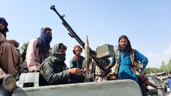 Schwer bewaffnete Taliban-Kämpfer fahren in einem Fahrzeug durch Mehtarlam, der Hauptstadt der Provinz Laghman © Str/XinHua/dpa Foto: Str/XinHua/dpa