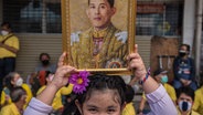Ein thailändisches Mädchen hält ein Porträt ihres Königs Maha Vajiralongkorn in die Höhe © picture alliance / ZUMAPRESS.com | Peerapon Boonyakiat Foto: Peerapon Boonyakiat