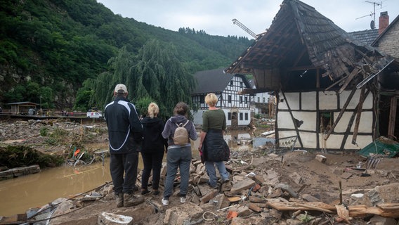 Menschen schauen in dem Ort Schuld im Kreis Ahrweiler nach dem Unwetter auf die Zerstörungen.  Foto: Harald Tittel/dpa