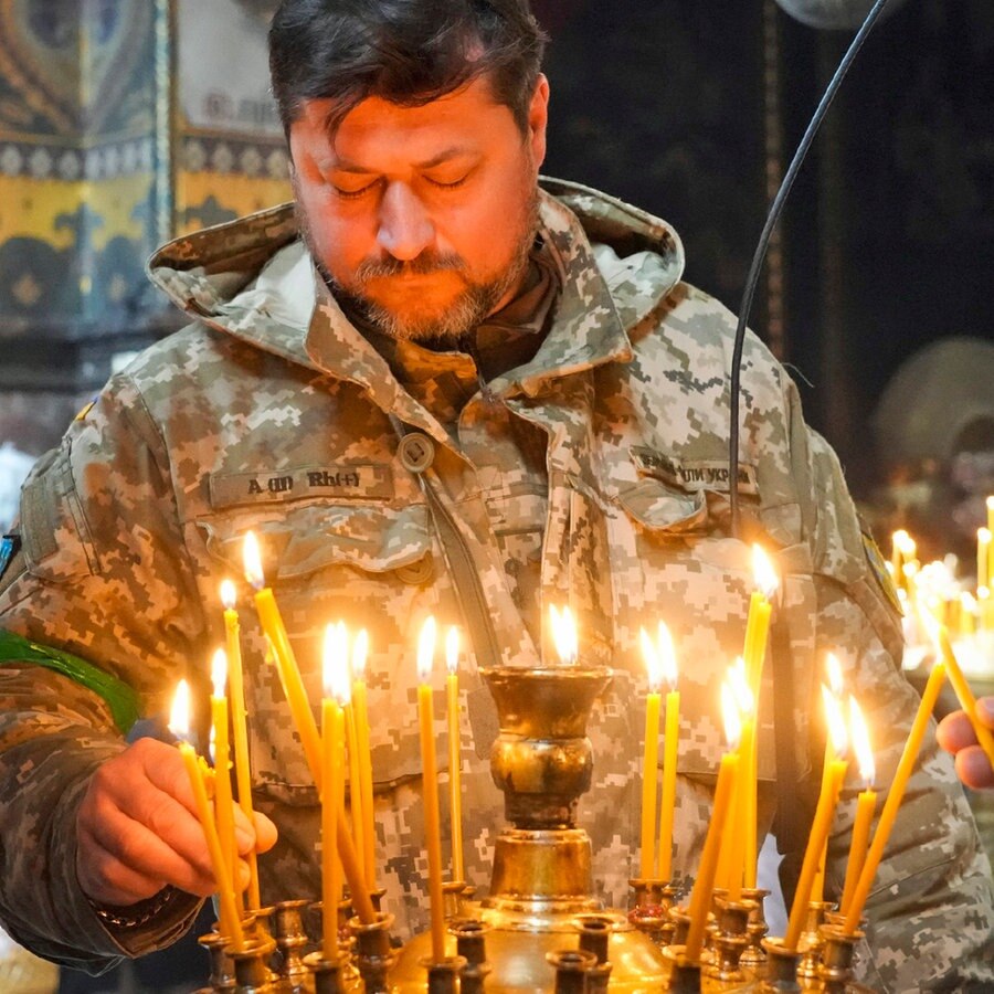 Ein ukrainischer Soldat entzündet Kerzen in der Wolodymyski-Kathedrale in Kiew während der orthodoxen Osterfeierlichkeiten. © AP/dpa Foto: Efrem Lukatsky