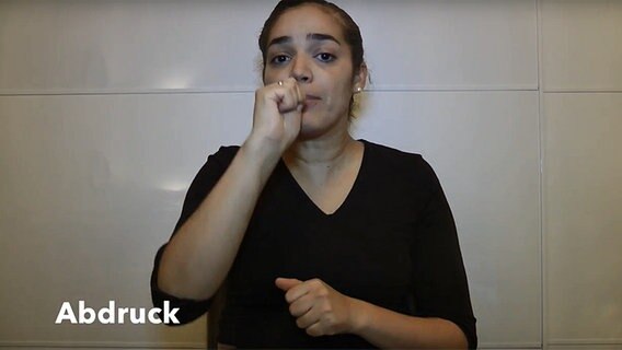 Ausschnitt aus einem YouTube-Video: Eine Zahnärztin erklärt den Gebärdensprache-Begriff "Abdruck", indem sie ihre rechte Hand zum Mund führt. © DGS Zahnarztpraxis/Screenhot YouTube 