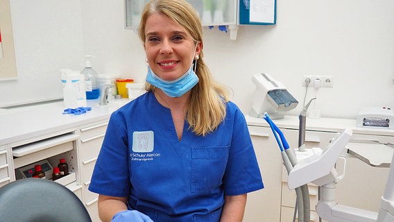 Kinga Ostrowski, gehörlose Zahnarzthelferin, mit einem herunter geklappten Mundschutz. © NDR Info Foto: Bettina Less