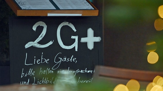 Auf einer Tafel vor dem Eingang eines Restaurants befindet sich ein Hinweis auf die 2G PLUS-Verordnung.  © imago images/ Sven Simon Foto: Frank Hörmann / Sven Simon