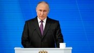 Wladimir Putin, Präsident von Russland, steht bei einer Rede an einem Pult mit Mikrofon. © dpa bildfunk/AP Foto: Alexander Zemlianichenko