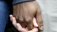 Eine dunkelhäutige und eine weiße Hand halten zusammen. © dpa picture alliance Foto: Salvatore Di Nolfi