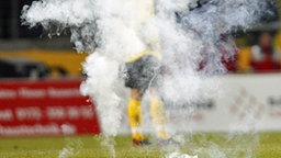 Eine Rauchbombe auf dem Rasen eines Fußballstadions. © dpa Foto: Thomas Eisenhuth