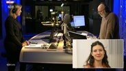 Moderator Andreas Kuhnt (r.) steht mit Norderstedts Oberbürgermeisterin Elke Christina Roeder im Studio von NDR Info. Unten rechts ist ein Bild der Politik-Analystin Helena Hahn eingeblendet. © NDR 