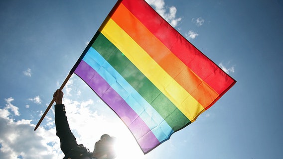 Ein Mann hält eine Regenbogen-Fahne während einer Schwulen-Parade. © dpa picture alliance Foto: Wojtek Radwanski