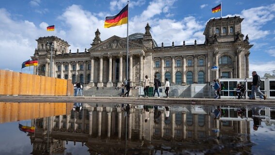 Berlin: Passanten gehen beim sonnigen Wetter an dem Reichstagsgebäude vorbei. © dpa Foto: Monika Skolimowska