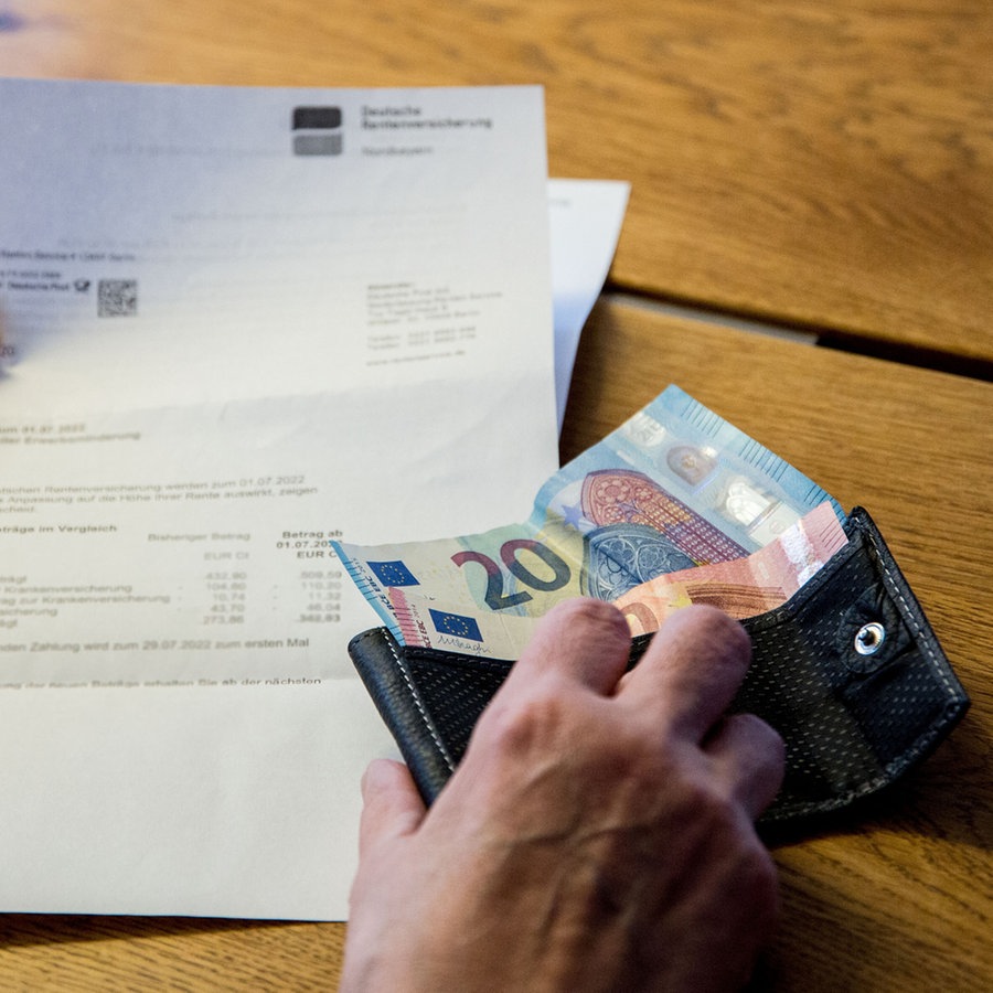 Eine Person schaut sich ein Schreiben der Deutschen Rentenversicherung an und hält dabei eine Geldbörse mit wenig Bargeld in den Händen. © picture alliance / Fotostand Foto: Fotostand / K. Schmitt