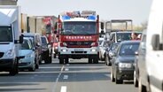 Ein Feuerwehrfahrzeug fährt durch die Rettungsgasse im Stau hinter einer Unfallstelle.  Foto: Jan Woitas