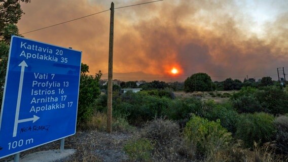 Ein Verkehrsschild auf der griechischen Insel Rhodos weist auf den Ort Vati hin, wo es seit mehreren Tagen brennt. © dpa Foto: Christoph Reichwein