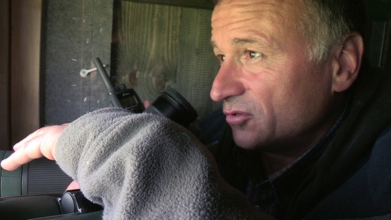 Vogelkundler Markus Risch mit Fernglas in einer Beobachtungshütte. © NDR 