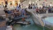 Touristen sitzen in Rom im Schatten an der Fontana della Barcaccia, ein Brunnen auf der Piazza di Spagna, vor der Spanischen Treppe © dpa Foto: Robert Messer