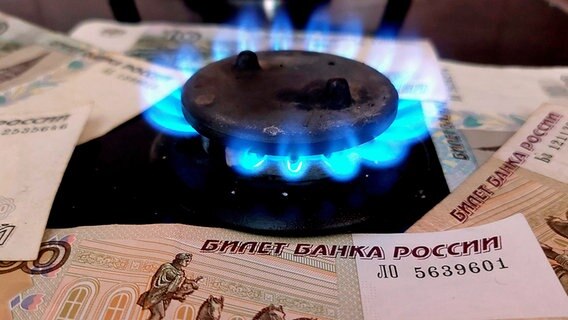 Mehrere Rubelscheine liegen um eine brennende Flamme auf einem Gasofen herum. © dpa picture alliance / PIXSELL Foto: Dusko Jaramaz