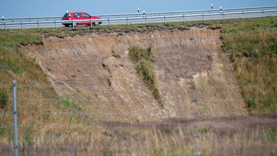 Ein Auto fährt auf der B96 bei Samtens. Im Vordergrund ist abgerutschte Erde an einem Hang zu sehen. © dpa bildfunk Foto: Stefan Sauer