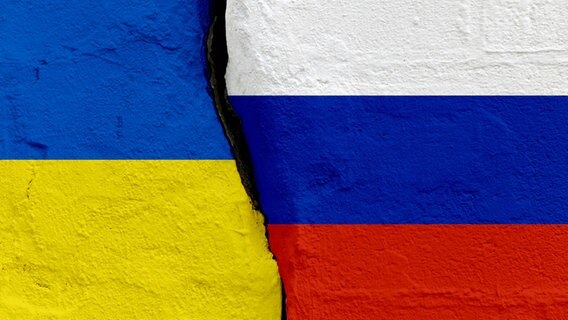 Symbolhaft ist ein Riss zwischen der ukrainischen und der russichen Flagge zu sehen. © picture alliance / SULUPRESS.DE 