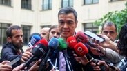 Spaniens Ministerpräsident Pedro Sanchez von der Sozialistischen Arbeiterpartei (PSOE) spricht in mehrere Mikrofone von Journalisten. © dpa-Bildfunk/EUROPA PRESS Foto: Ricardo Rubio