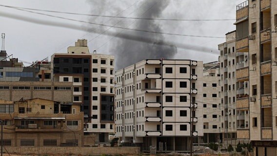 Während eines Einsatzes der syrischen Sicherheitskräfte in der Stadt Scharaja steigt Rauch hinter einem Gebäude auf. © AP/dpa Foto: Omar Albam