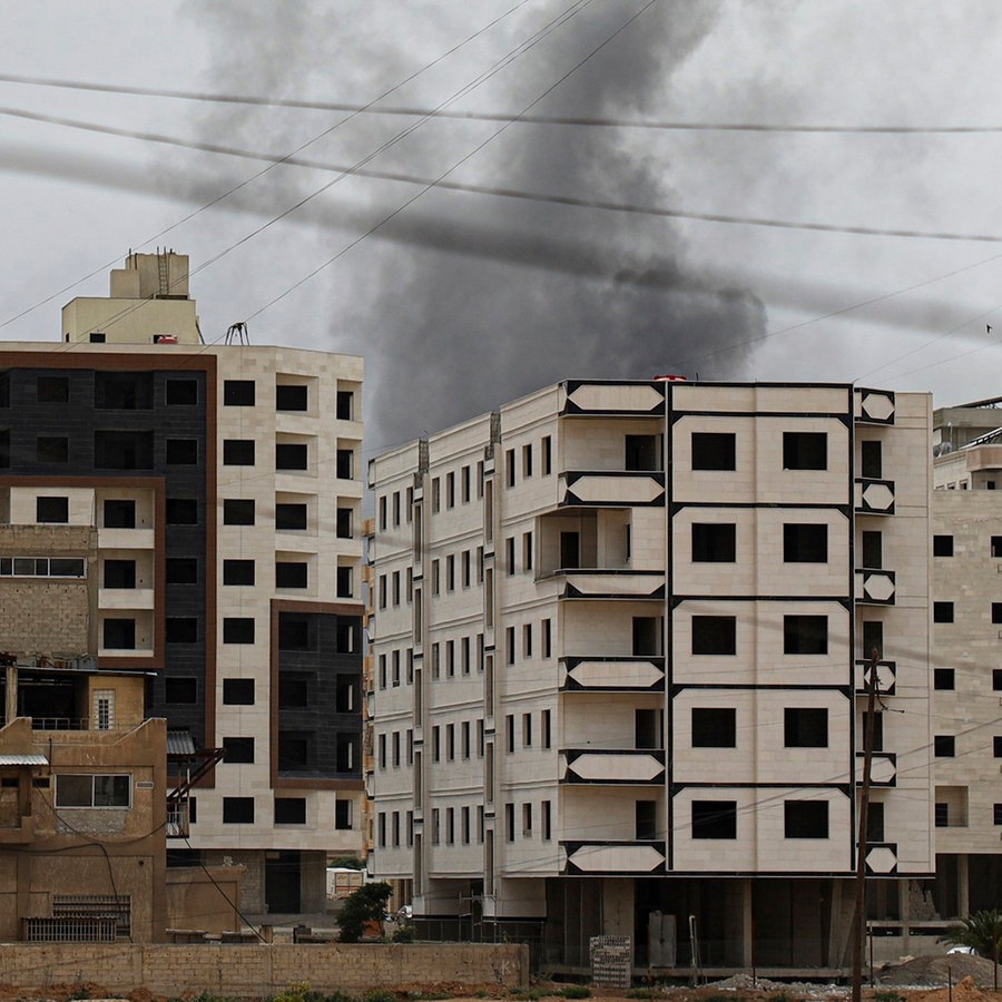 Während eines Einsatzes der syrischen Sicherheitskräfte in der Stadt Scharaja steigt Rauch hinter einem Gebäude auf. © AP/dpa Foto: Omar Albam