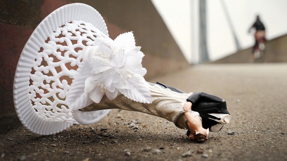 Der Rest der Dekoration einer Hochzeitstorte - die Brautpaarfiguren - liegt auf einer Brücke. © picture alliance/dpa/Martin Gerten Foto: Martin Gerten