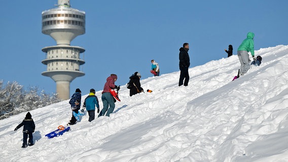 Zahlreiche Menschen stehen in München auf einer zugeschneiten Hangfläche im Olympiapark in München. © dpa bildfunk Foto: Sven Hoppe