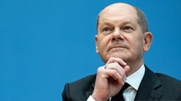 Olaf Scholz (SPD), designierter Bundeskanzler, sitzt in der Bundespressekonferenz. Er hat die Hand am Kinn und wirkt nachdenklich. © dpa-Bildfunk 