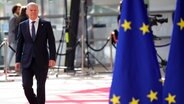 Bundeskanzler Olaf Scholz ist beim EU-Gipfel in Brüssel neben EU-Flaggen zu sehen. © Olivier Matthys/AP Pool/dpa 