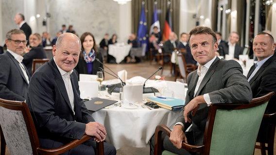 Bundeskanzler Olaf Scholz (SPD, l.) und Emmanuel Macron, Staatspräsident von Frankreich, blicken bei einer Veranstaltung in Hamburg in die Kamera. © dpa bildfunk/Pool AP Foto: Markus Schreiber