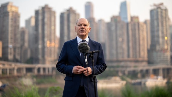 Bundeskanzler Olaf Scholz (SPD) spricht bei einem Statement zur Situation in Israel und zur Reise durch China, im Hintergrund Hochhäuser der Stadt Chongqing. © dpa-Bildfunk Foto: Michael Kappeler