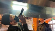 Jeremy Wrosch überprüft eine Dunstabzugshaube im Restaurant Speicherköck in Schwaan - rechts im Hintergrund sein Ausbilder dem Schornsteinfegermeister Michael Schmidt © NDR Foto: Wiebke Neelsen