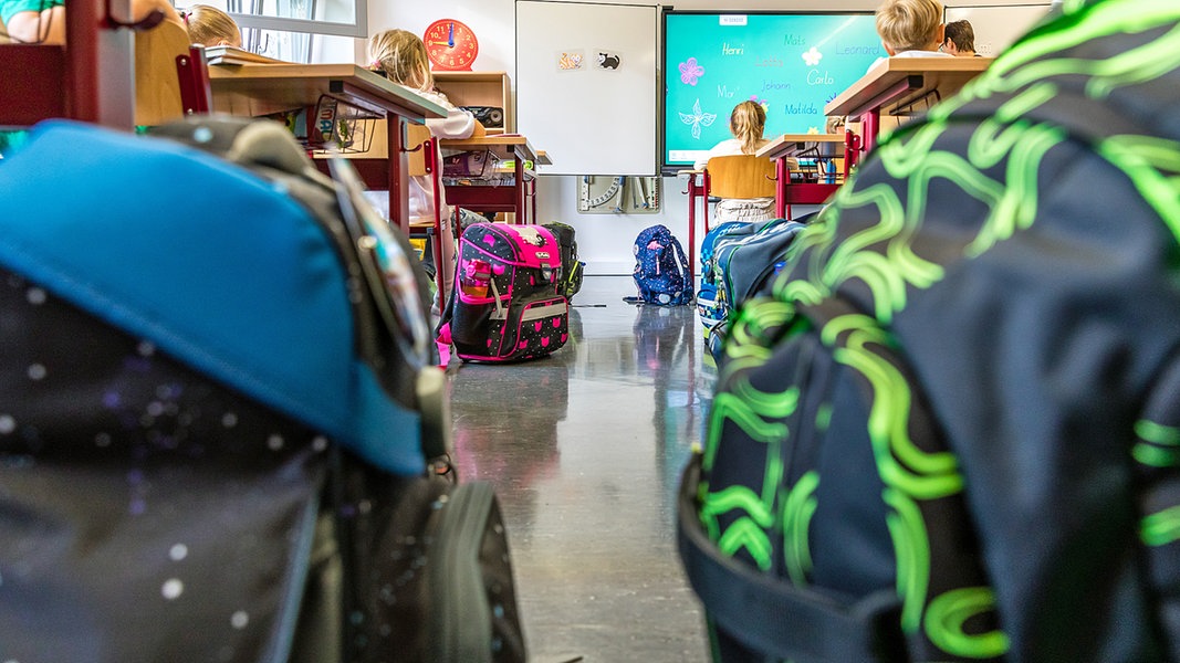 Schultaschen stehen in einem Klassenraum einer Grundschule auf dem Boden.