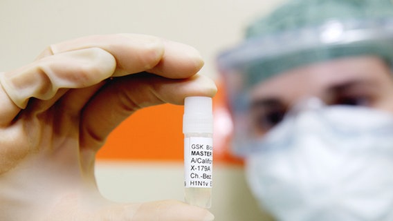 Ein Pharma-Mitarbeiter zeigt einen Behälter mit dem H1N1-Virus, der zur Beimpfung von Hühnereiern verwendet wird, um den Schweinegrippe-Impfstoff zu erhalten. © dpa Foto: Juliane Mostertz