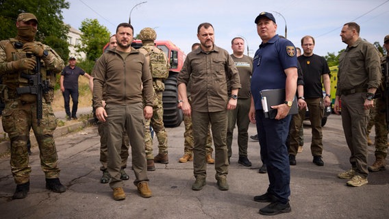 Der ukrainische Präsident Selenskyj und mehrere weitere Männer in Uniform stehen auf einer Straße in Cherson. © Uncredited/Ukrainian Presidential Press Office/AP/dpa Foto: Uncredited/Ukrainian Presidential Press Office/AP/dpa