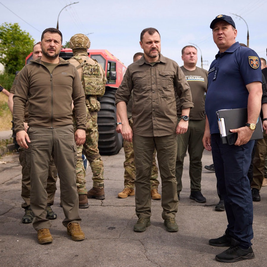 Der ukrainische Präsident Selenskyj und mehrere weitere Männer in Uniform stehen auf einer Straße in Cherson. © Uncredited/Ukrainian Presidential Press Office/AP/dpa Foto: Uncredited/Ukrainian Presidential Press Office/AP/dpa