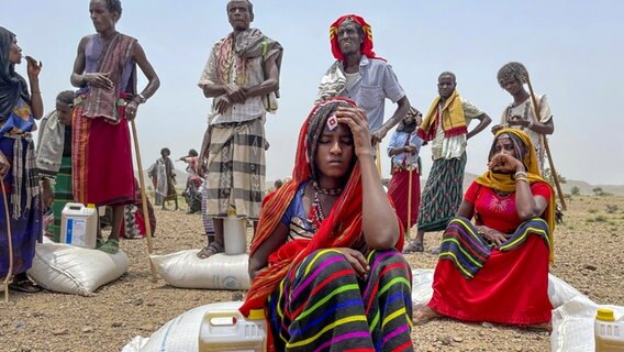 Erschöpfte Männer und Frauen mit Notrationen humanitärer Hilfe. © picture-alliance Foto: Claire Nevill