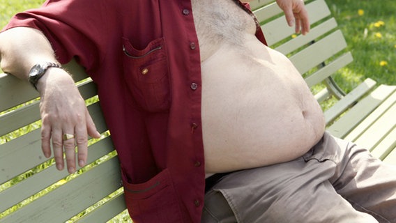 Ein Mann mit dickem Bauch sitz auf einer Bank © picture-alliance 