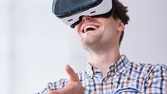 Mann trägt eine VR-Brille und lacht. © fotolia.com Foto: Photographee.eu