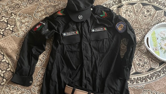 Eine Polizei-Uniform der Republik Afghanistan auf einem Teppich. © ARD 