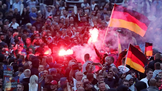 Am 27. August 2018 gehen Demonstranten der rechten Szene auf die Straße in Chemnitz, schwenken Deutschlandfahnen und zünden Pyrotechnik. © picture-alliance/dpa Foto: Jan Woitas