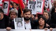 Gabriel Boric, Präsident von Chile, (Mitte l) und Menschen mit Bildern von Vermissten während einer Demonstration zum 50. Jahrestag des Militärputsches von General Pinochet vor dem Präsidentenpalast La Moneda. © picture alliance Foto: Esteban Felix