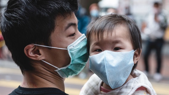 Ein chinesischer Vater und sein Kleinkind tragen einen Mundschutz © Aidan Marzo 
